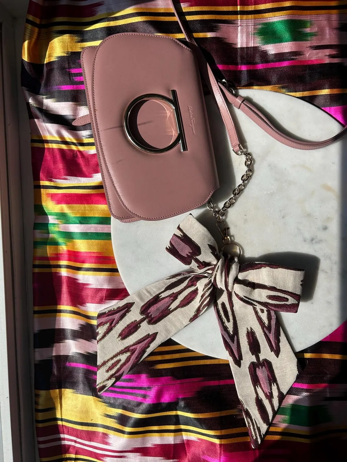 Close flat lay of the atlas ikat ribbon tied to the bag's chain strap on a marble surface
