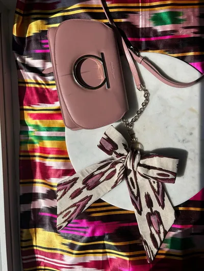Close flat lay of the atlas ikat ribbon tied to the bag's chain strap on a marble surface