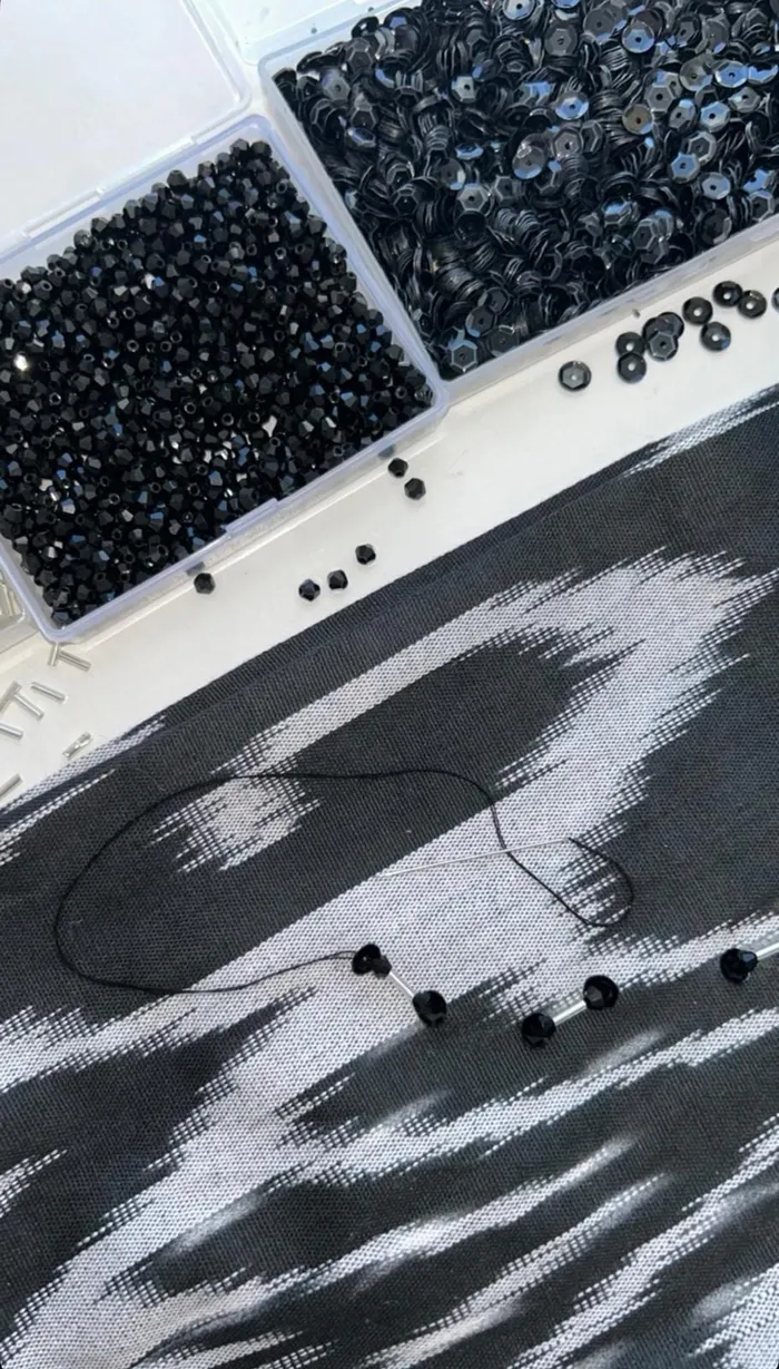 Hand-beading in progress on a black and cream atlas ikat baska skirt