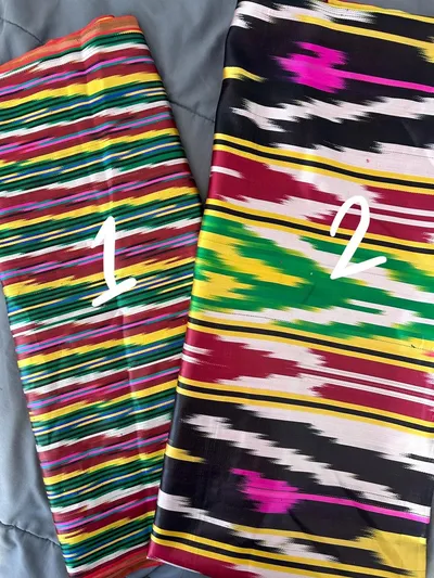 Two folded bolts of striped multicolor ikat silk fabric