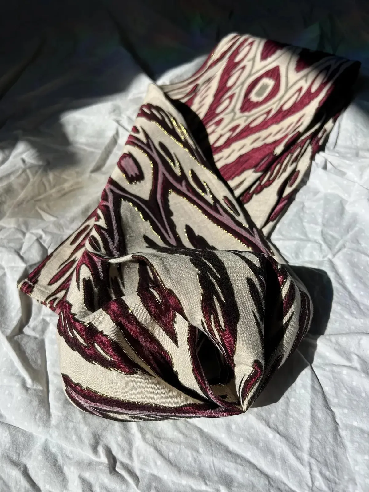 Atlas ikat neck scarf twisted into a loose knot showing the reverse side of the weave