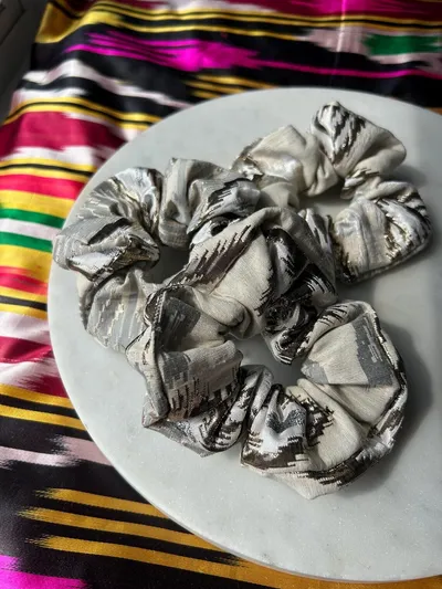 A metallic silver ikat scrunchie worn stacked on a wrist