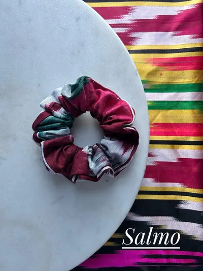 A maroon, white, and green plaid ikat scrunchie on a marble plate, labeled 'Salmo'