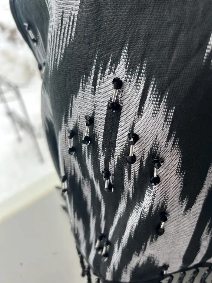 Macro close-up of hand-sewn beading along a resist-dyed atlas ikat edge