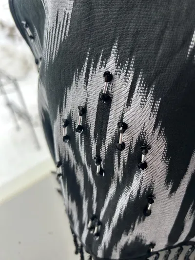 Close-up of black beaded fringe embellishment on a black-and-white atlas ikat vest