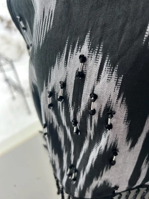 Close-up of black beaded fringe embellishment on a black-and-white atlas ikat vest