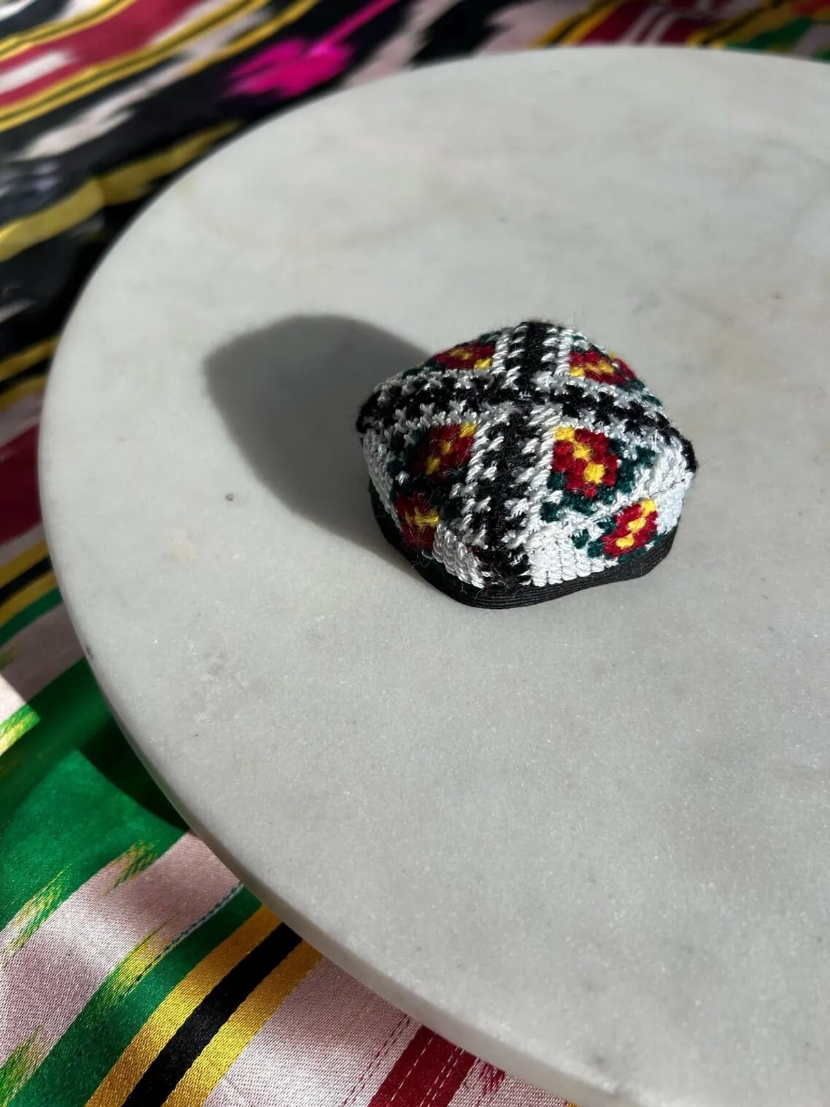 Embroidered doppi hair tie shown from another angle on a marble plate