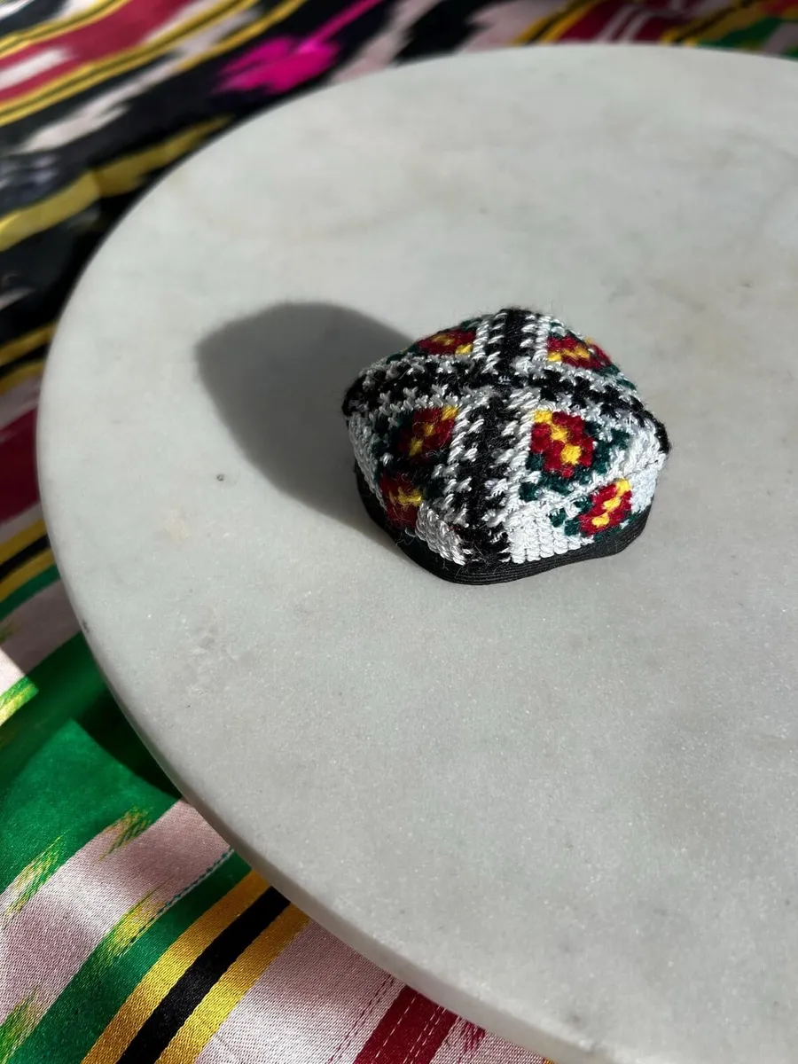 Embroidered doppi hair tie shown from another angle on a marble plate