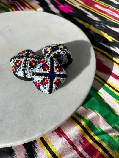 Three embroidered doppi hair ties grouped together on a marble plate