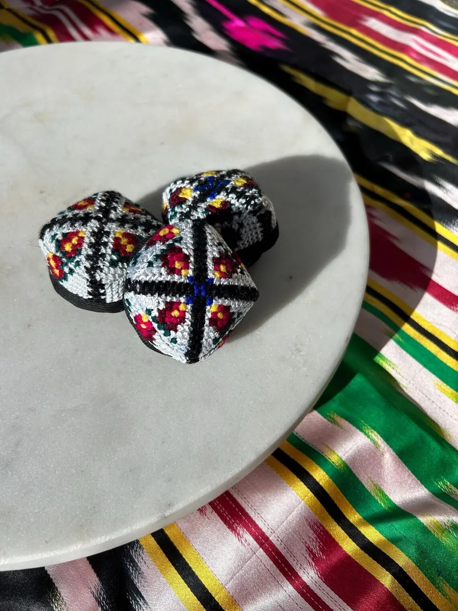 Three embroidered doppi hair ties grouped together on a marble plate