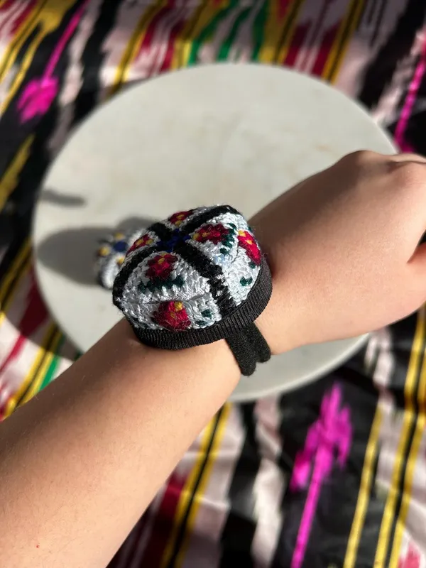 Embroidered doppi hair tie worn on a wrist