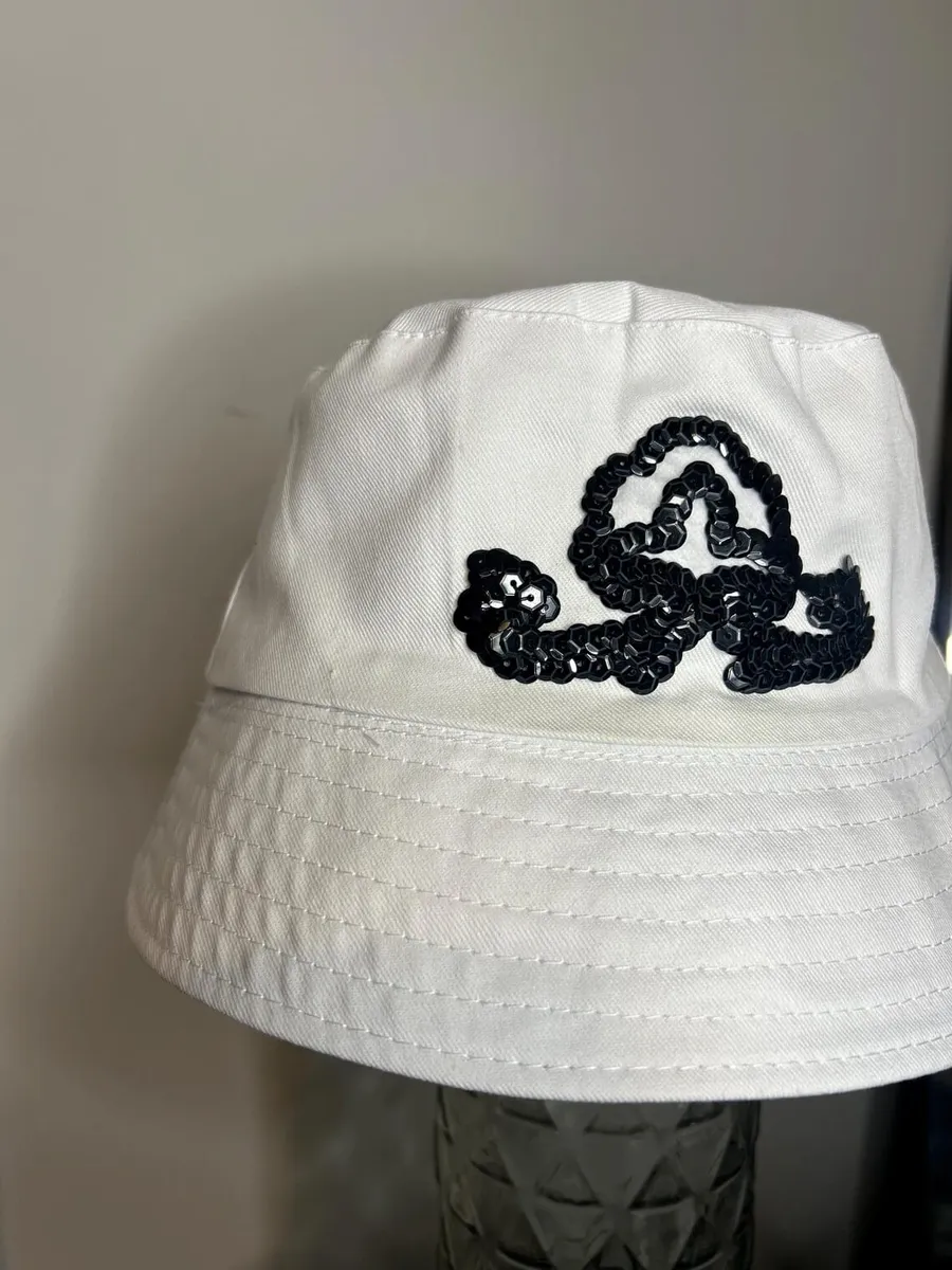 Close-up of a black sequin swirl emblem on a white bucket hat