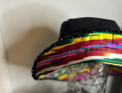 A black bucket hat with a multicolor ikat ribbon band and black beaded brim edge