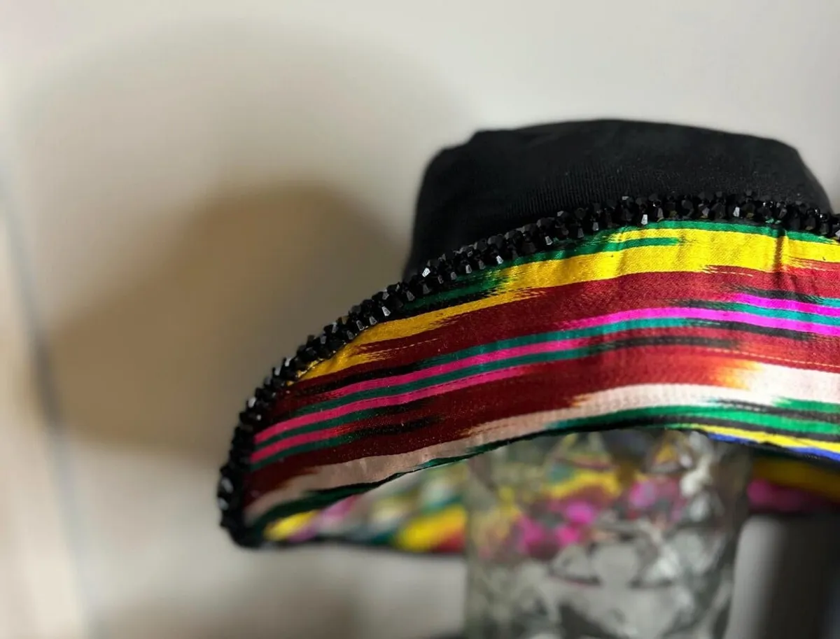 A black bucket hat with a multicolor ikat ribbon band and black beaded brim edge