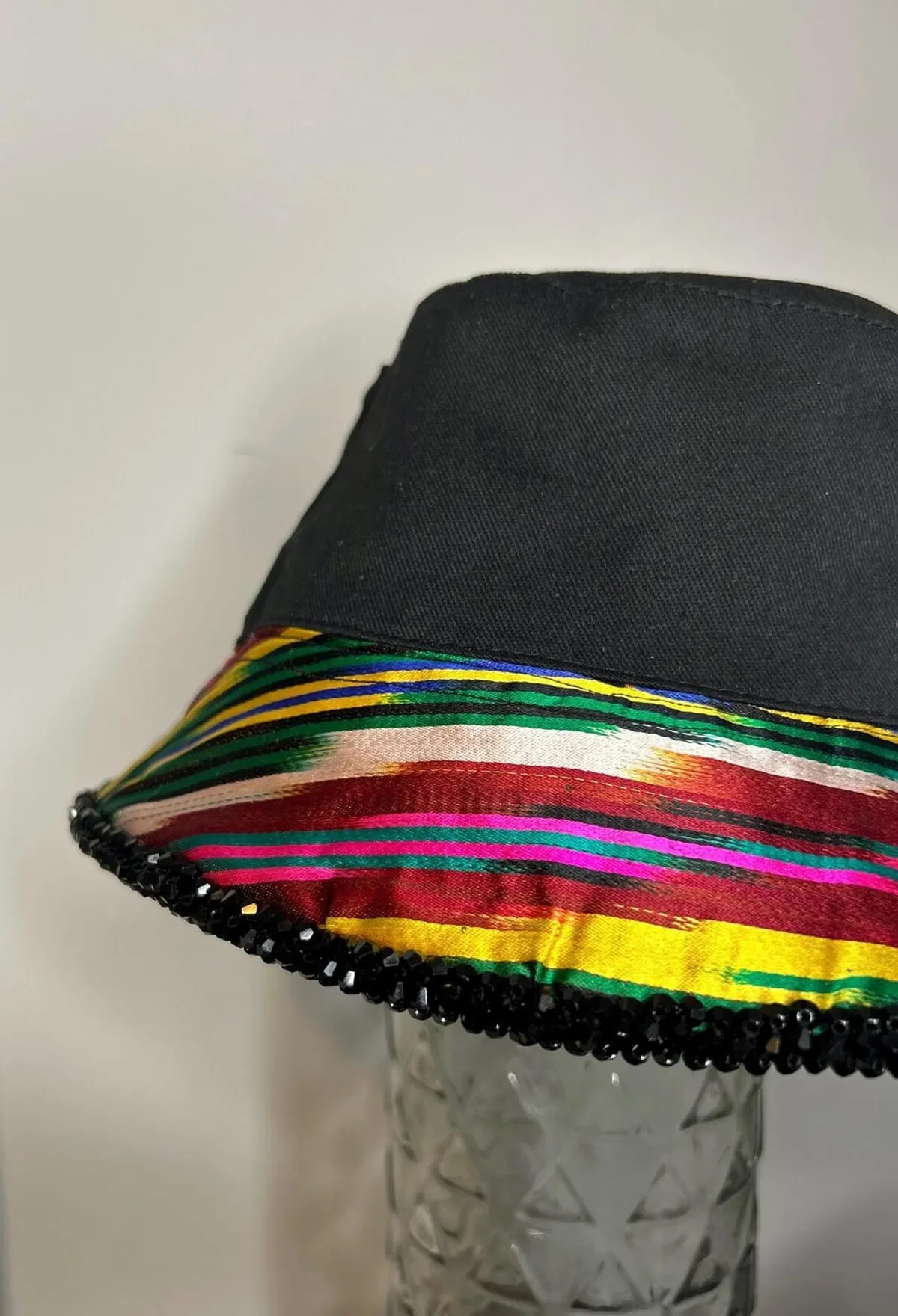 Close-up of the multicolor ikat ribbon trim and black beaded edge on a bucket hat