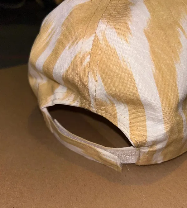 Back view of a gold and cream ikat baseball cap showing the adjustable strap