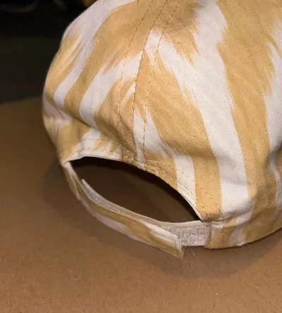 Back view of a gold and cream ikat baseball cap showing the adjustable strap